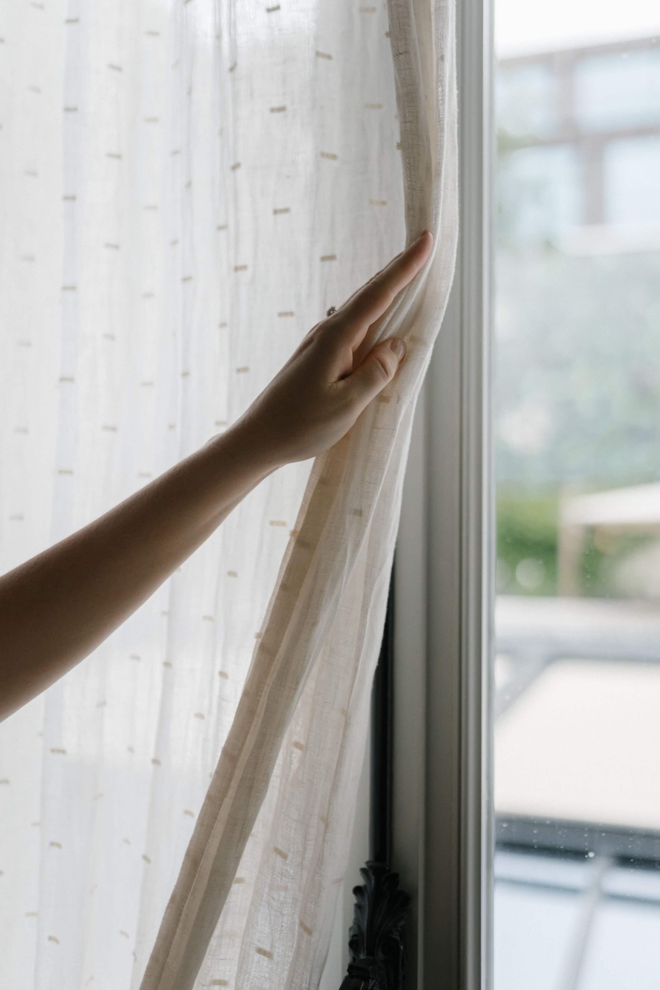 elegant woman's hand opening curtain on european window .jpg