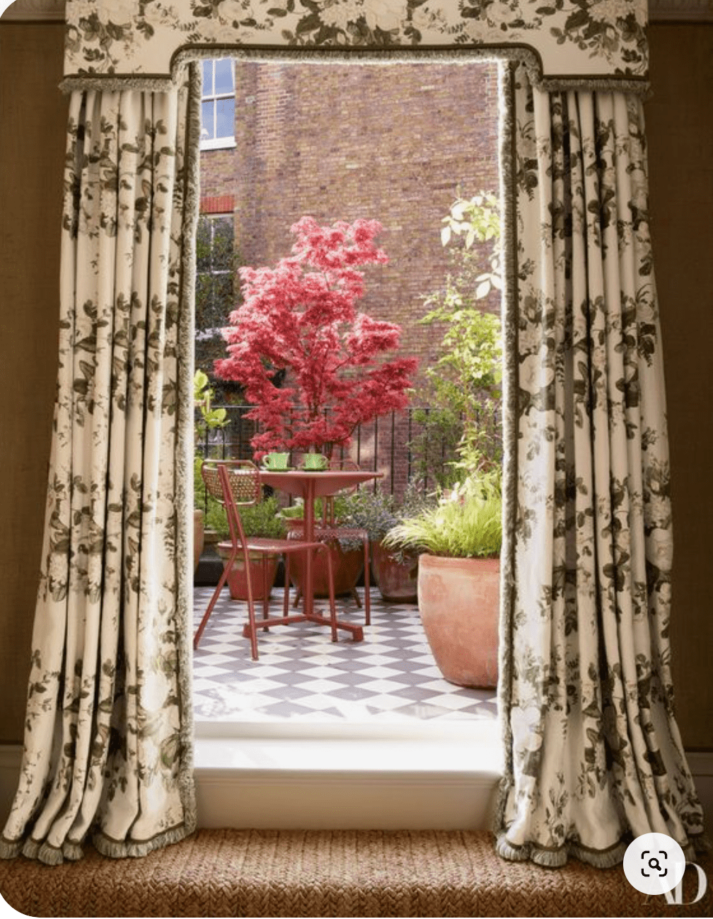 View of a backyard patio through patterned curtains.png