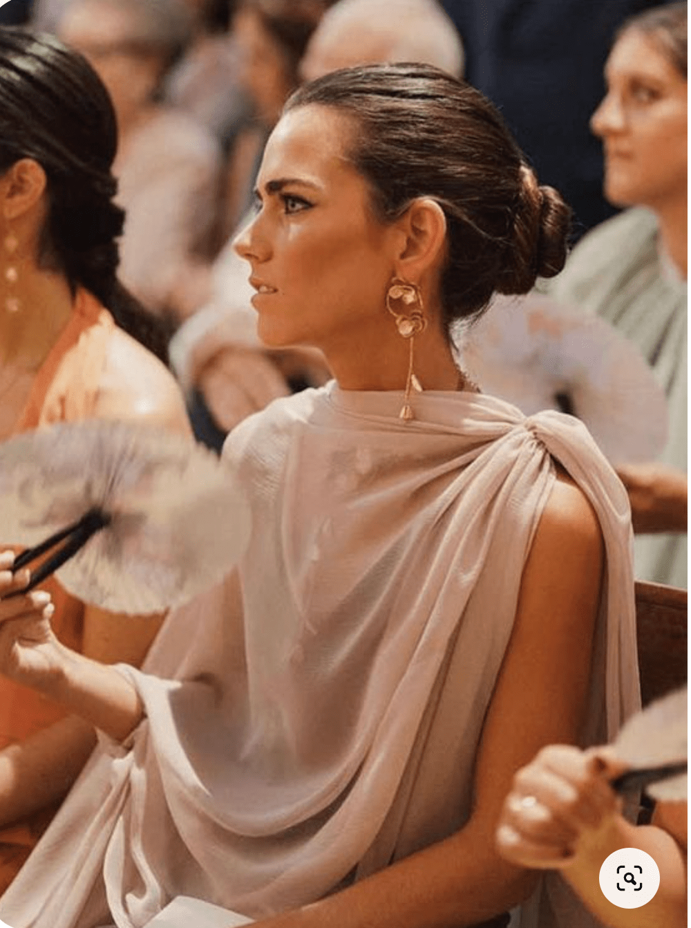 Woman attending a runway event wearing a soft pink silk gown.png