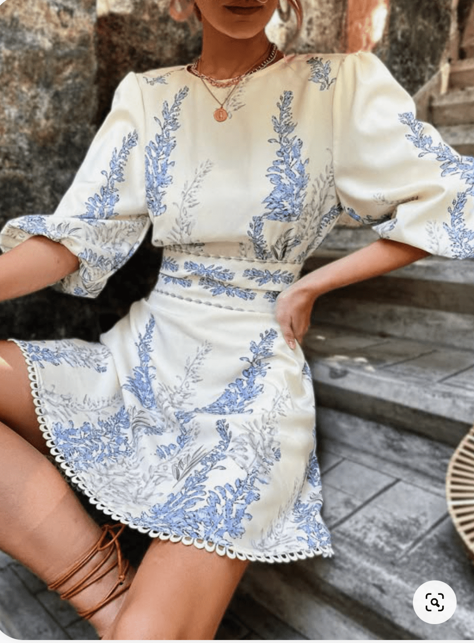 Woman wearing a white dress with elegant blue flower pattern.png